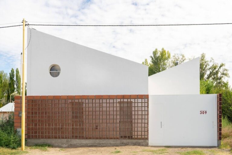Fachada de casa de 2 niveles color blanco con un muro de celosia de barro. Casa MP por EME arquitectura