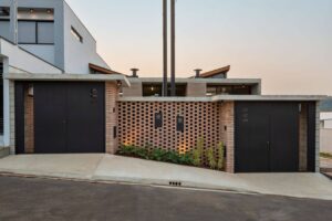 Casa Bohemia en Brasil. Fachada de casa en desnivel, de ladrillo y portones negro