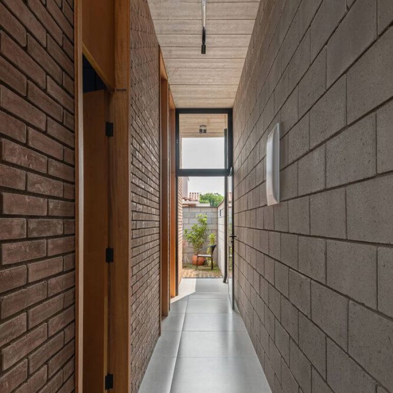 Casa Bohemia en Brasil. pasillo a patio trasero con muros de ladrillos aparente