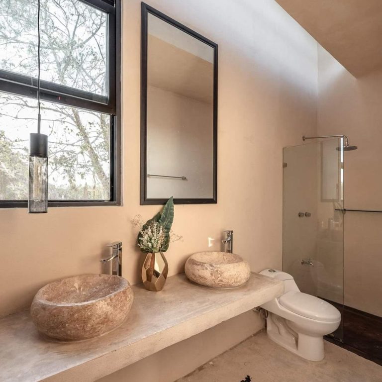 Casa Bungalow en Yucatán: Diseño residencial por V+A Arquitectura. Baño con lavabos de piedra, inodoro y regadera de divida por cristal