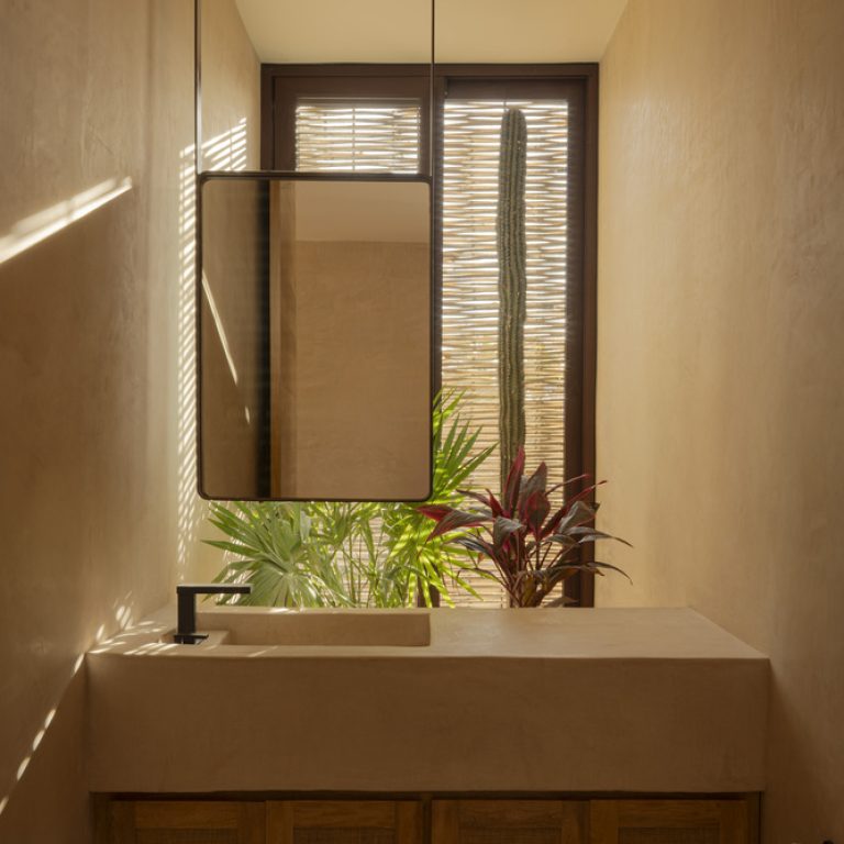 Baño con celosía de madera y vegetación en Casa Ka'anche