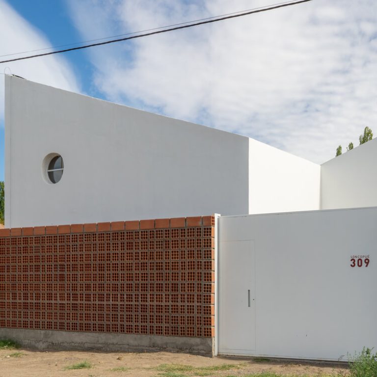 Fachada de casa de 2 niveles color blanco con un muro de celosia de barro