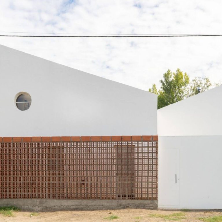 Fachada de casa de 2 niveles color blanco con un muro de celosia de barro. Casa MP por EME arquitectura