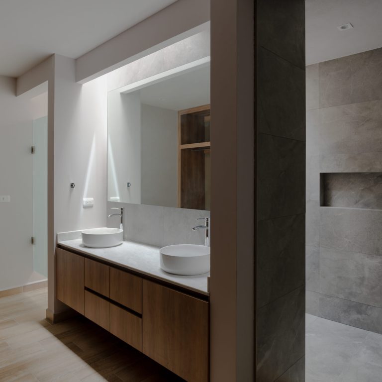 Baño moderno con tono grises y blancos, condos lavabos, espejo y mueble dee madera