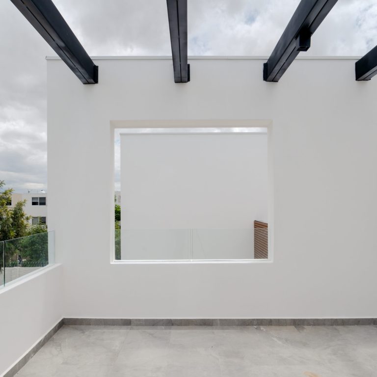 terraza en fachada con muros blanco y un pergolas de de acero color negro