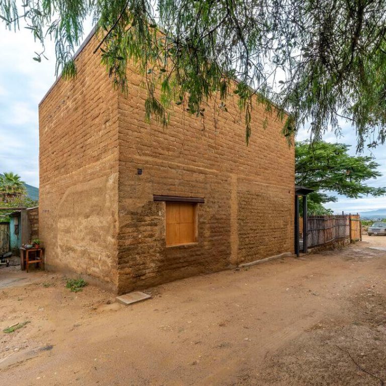Fachada de casa de adobe con ventana de madera. Casa taller Plúmula en Oaxaca por Espacio 18 Arquitectura