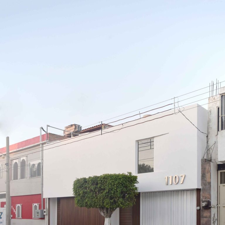 Fachada de casa color blanco moderna con detalles de madera en puertas. Reforma Casa AL en Guanajuato