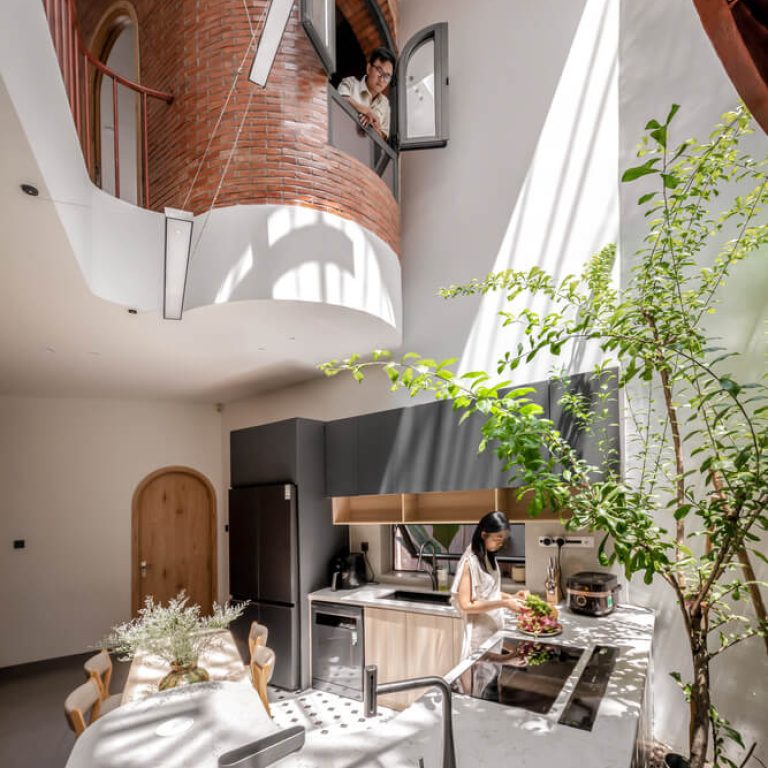 Cocina moderna de madera a doble altura, con escalera helicoidal color rojo