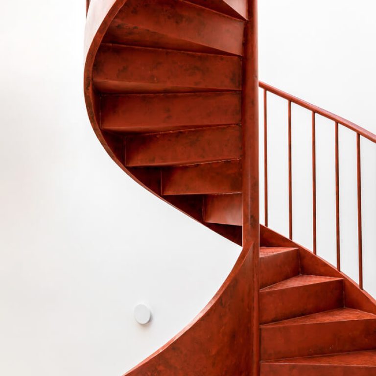 Escalera de caracol moderna color rojo de acero, escalera escultural, jardín interior en escalera