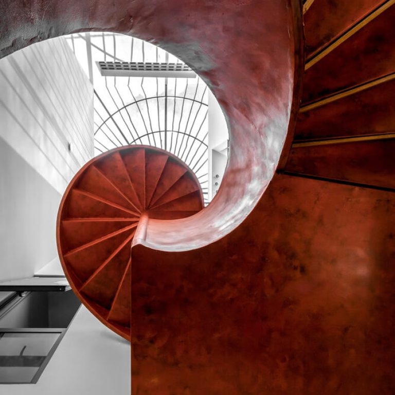 Escalera de caracol moderna color rojo de acero, escalera escultural, jardín interior en escalera